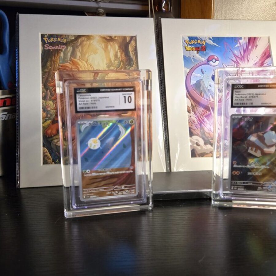 Two CGC Gem Mint 10 Pokemon cards displayed in Podium acrylic cases on a desk